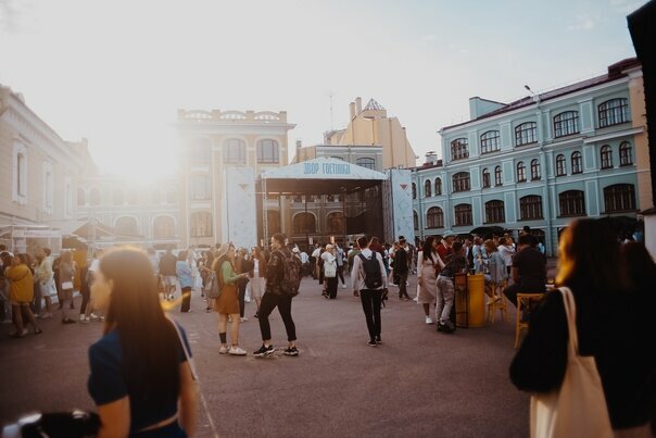 Гости летнего фестиваля во внутреннем дворе Гостиного Двора на закате.